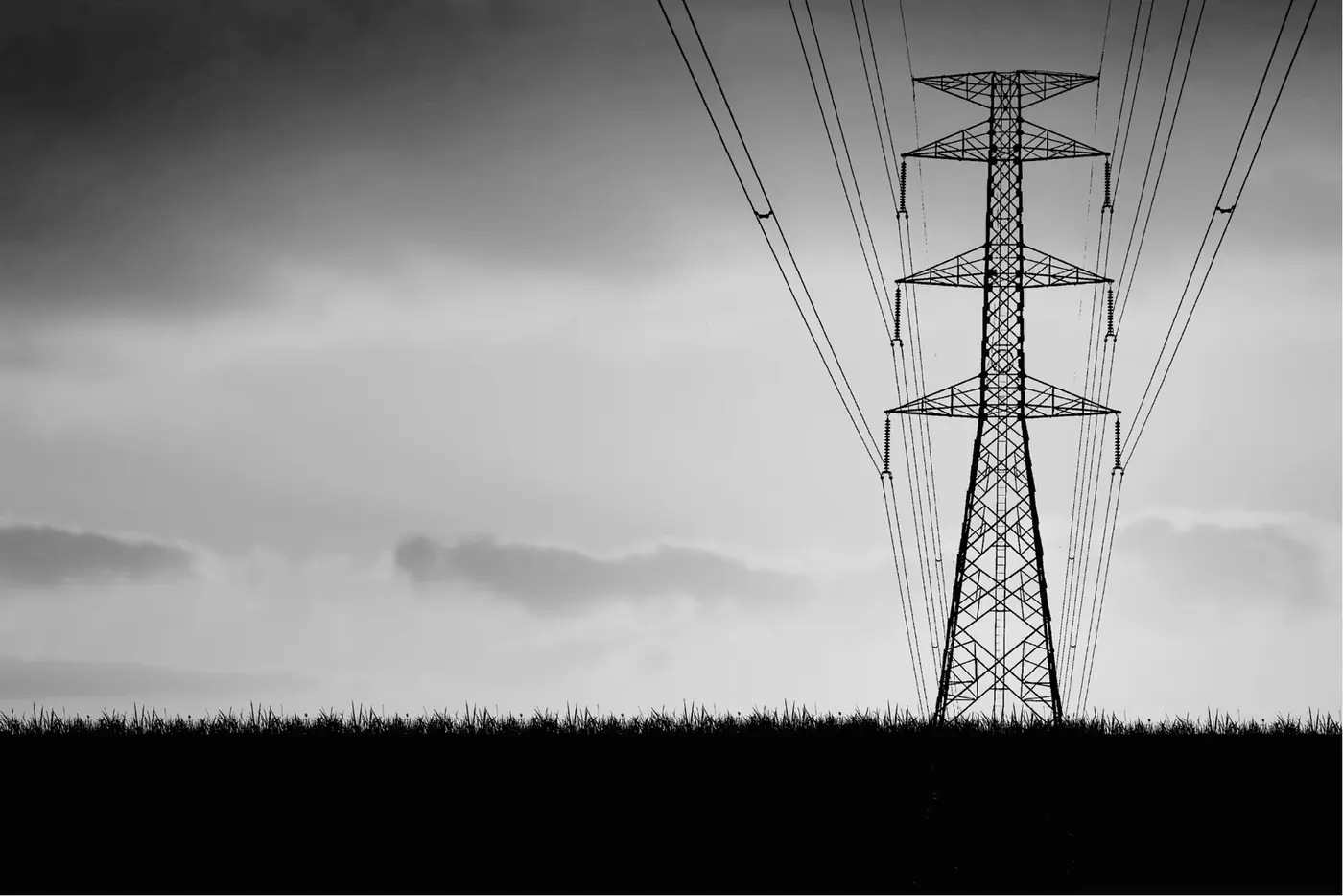 Power lines and a transmission tower against an overcast sky.